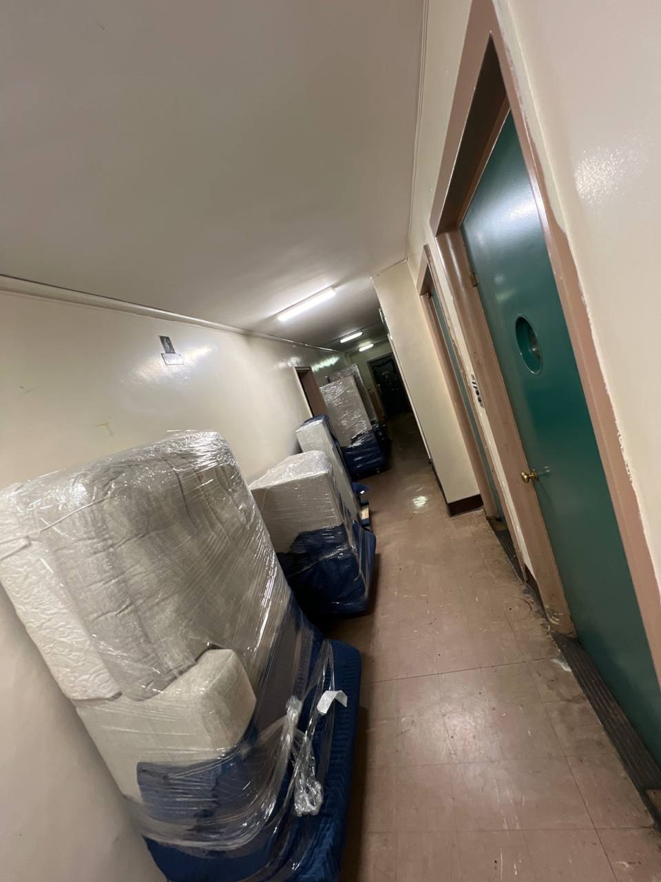 Wrapped furniture lined up on dollies in a building hallway